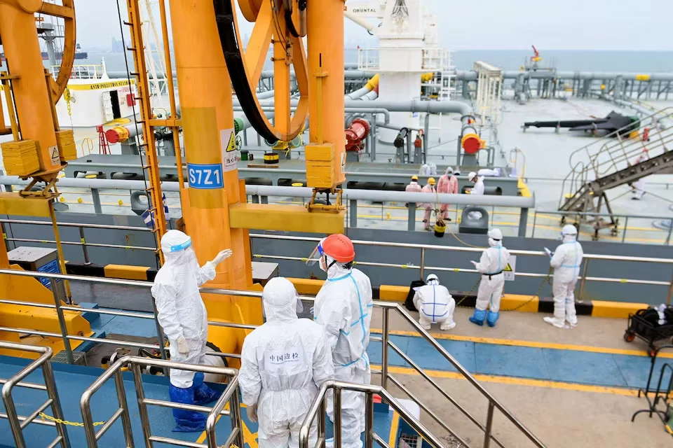Immigratie-inspecteurs controleren een tanker in de haven van Qingdao.