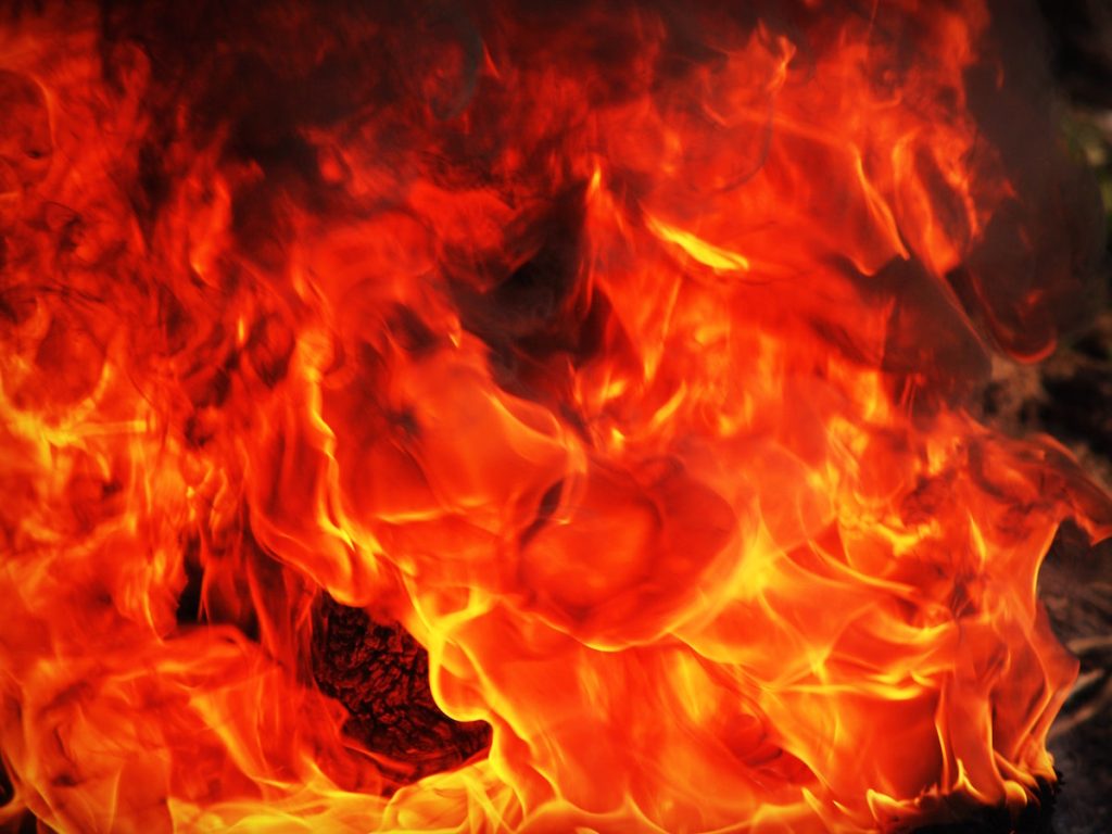 Gedeeltelijk verbrande houten woning in aanbouw aan de Heivlinderweg in Suriname, met brandschade aan de hoeken.