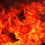 Gedeeltelijk verbrande houten woning in aanbouw aan de Heivlinderweg in Suriname, met brandschade aan de hoeken.